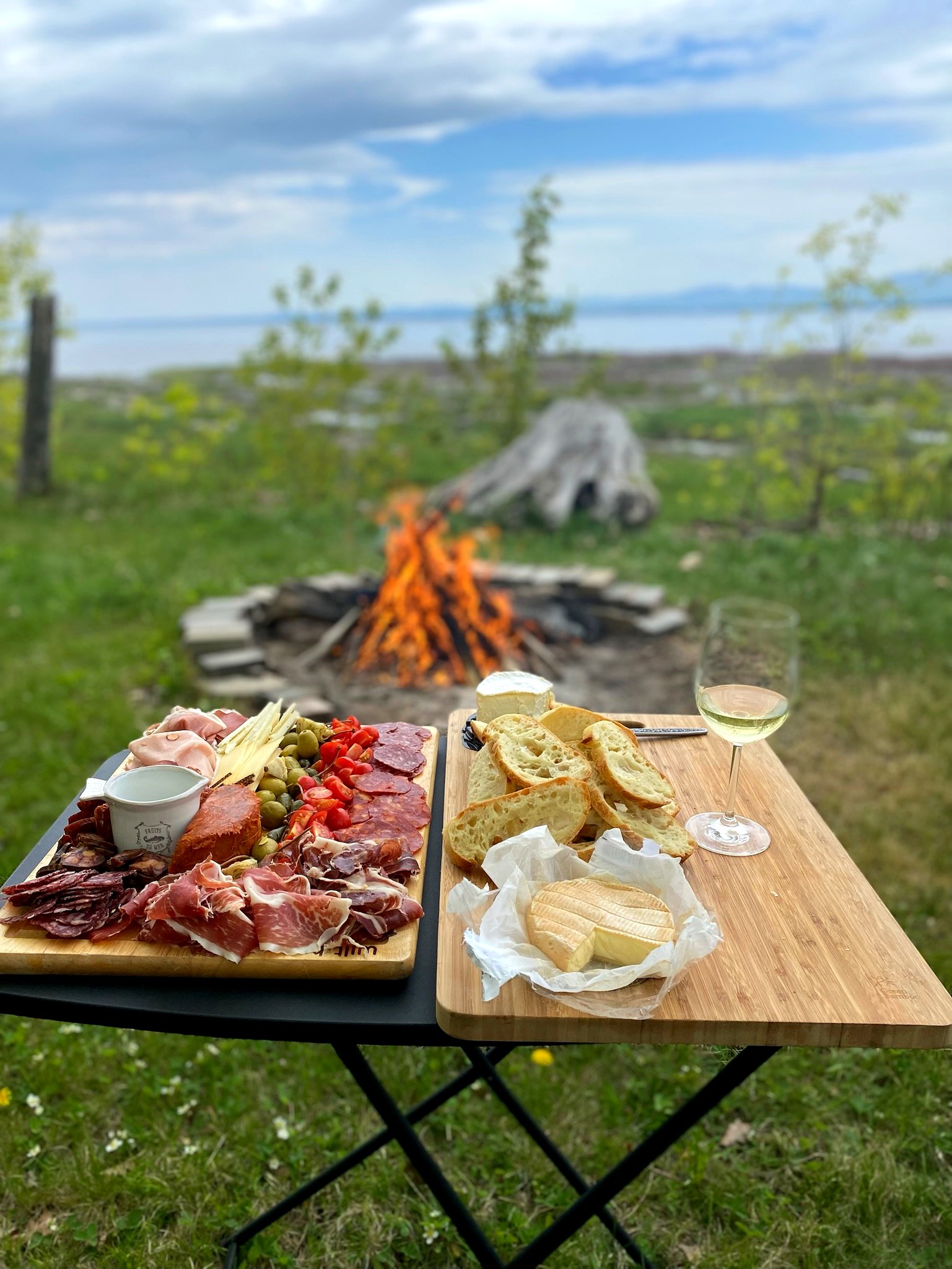 Planche de charcuterie devant le feu de camp et le fleuve